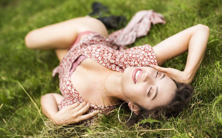 A beautiful woman lies on the grass
