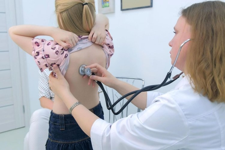 The doctor listens to the girl with a stethoscope